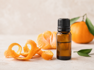 zestes de mandarine et flacon d'huile essentielle sur fond neutre