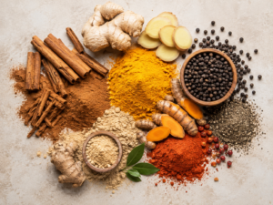 Épices de cuisine en tas colorés (cannelle, curcuma, gingembre, poivre) sur fond neutre, vue de dessus