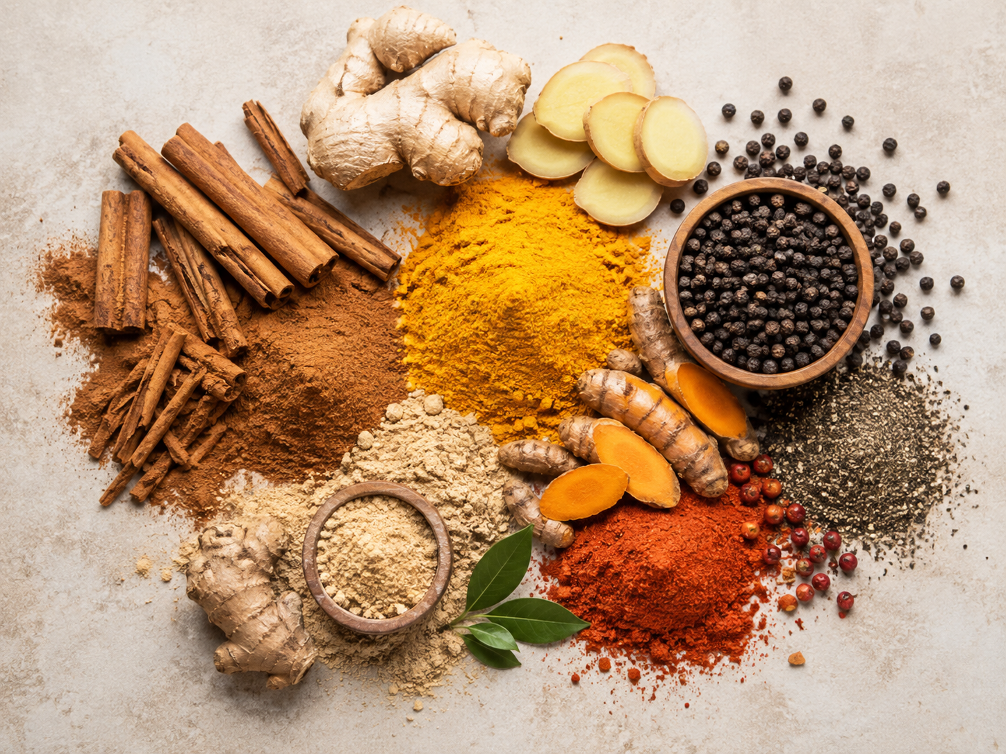 Épices de cuisine en tas colorés (cannelle, curcuma, gingembre, poivre) sur fond neutre, vue de dessus